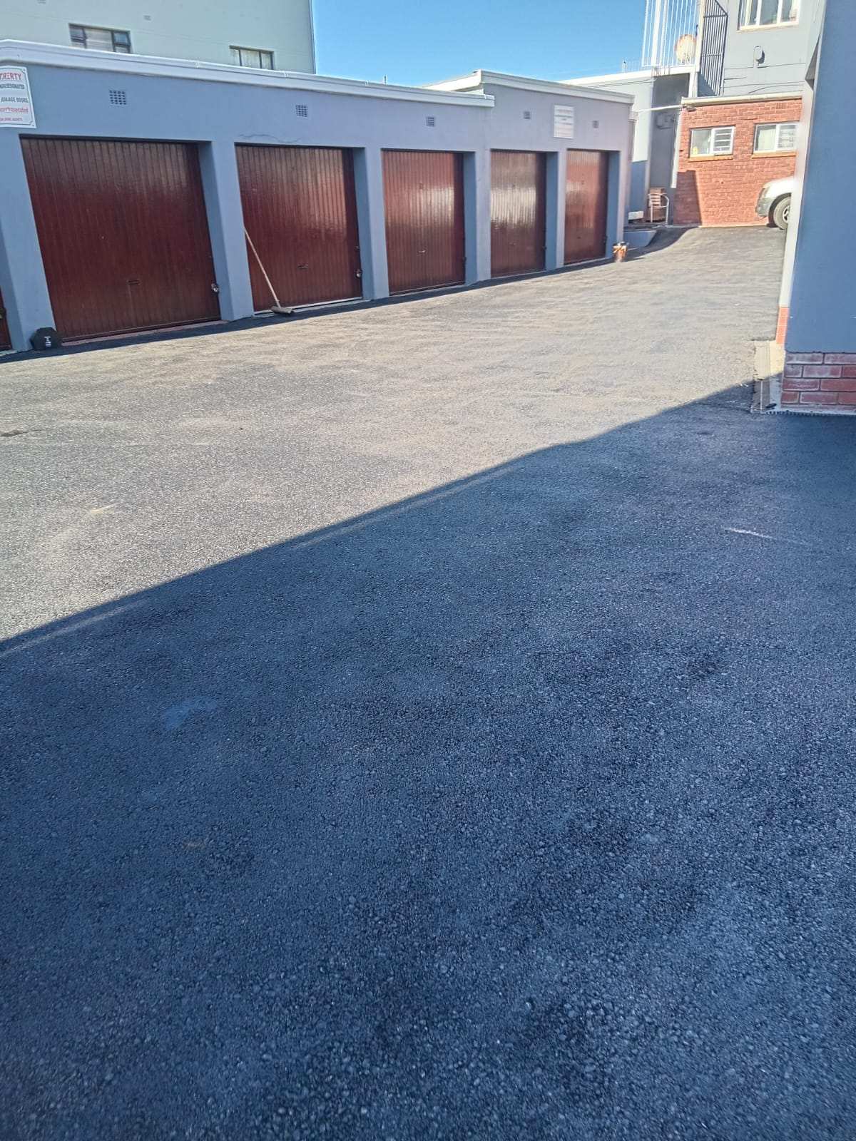 Finished asphalt surface in front of a row of garage units