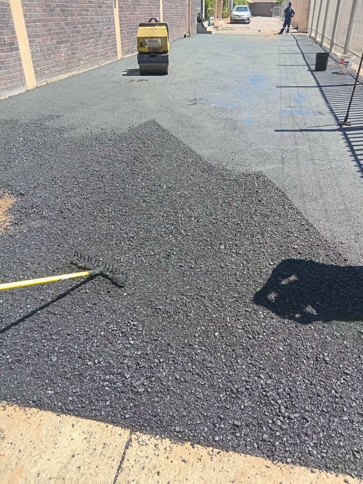 Pile of hot asphalt on site with a rake, ready to spread